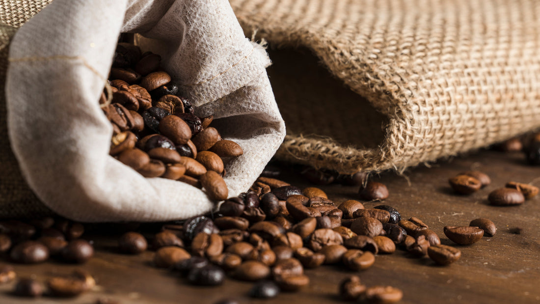 Roasted African coffee beans spilling from burlap sacks onto a wooden table.