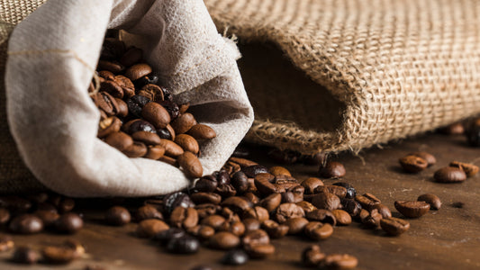 Roasted African coffee beans spilling from burlap sacks onto a wooden table.
